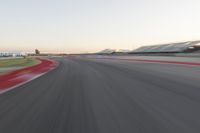 the view from the back of a racing car's car as it speeds along a track at sunset