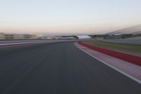 an image of motion blur in front of a car on a race track at dusk