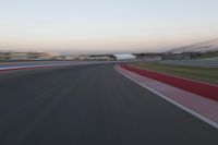 an image of motion blur in front of a car on a race track at dusk