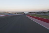 an image of motion blur in front of a car on a race track at dusk