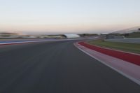 an image of motion blur in front of a car on a race track at dusk