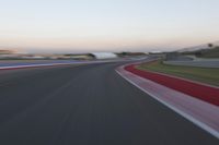 an image of motion blur in front of a car on a race track at dusk