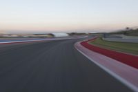 an image of motion blur in front of a car on a race track at dusk