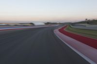 an image of motion blur in front of a car on a race track at dusk