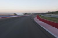 an image of motion blur in front of a car on a race track at dusk