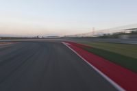 a very close shot of a car driving on the race track at dusk time with motion blur