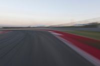 a very close shot of a car driving on the race track at dusk time with motion blur