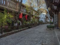 some old buildings near the sidewalk and one is leaning on a fence to pick up something from