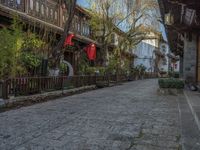 some old buildings near the sidewalk and one is leaning on a fence to pick up something from