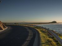 a lone road winds through the ocean beside a beach side area on the shoreline road