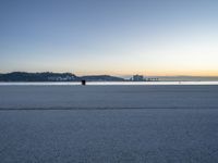 the fire hydrant is near the water in a distance on a city beach during the day