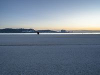 the fire hydrant is near the water in a distance on a city beach during the day