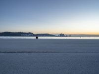 the fire hydrant is near the water in a distance on a city beach during the day