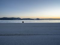 the fire hydrant is near the water in a distance on a city beach during the day