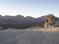 a person riding a horse on top of a rocky field under mountains in the background