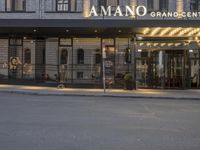 a person is outside the amano grand - center hotel entrance at night with no lights