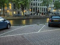 two cars parked in the parking lot next to water in the background at dusk in amsterdam