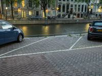 two cars parked in the parking lot next to water in the background at dusk in amsterdam