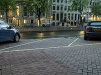 two cars parked in the parking lot next to water in the background at dusk in amsterdam