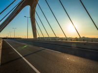 sun setting over the bridge, with cars driving along in distance, on a bridge