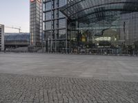 an empty area surrounded by stone bricks, on which two buildings have glass front entrances