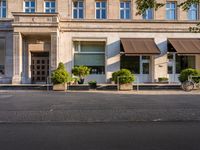 an outside view of a city building that has two bikes outside and a tree in front