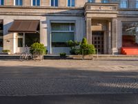 an outside view of a city building that has two bikes outside and a tree in front