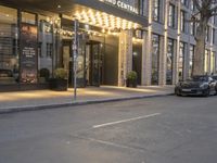 a luxury hotel in the city on the corner of the street, with the entrance lit up for evening