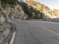 a scenic mountain road with a steep cliff behind it on a cloudy day in autumn