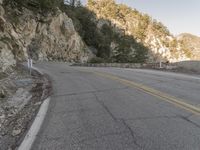 a scenic mountain road with a steep cliff behind it on a cloudy day in autumn