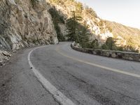 a scenic mountain road with a steep cliff behind it on a cloudy day in autumn