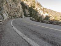 a scenic mountain road with a steep cliff behind it on a cloudy day in autumn