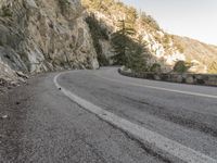 a scenic mountain road with a steep cliff behind it on a cloudy day in autumn