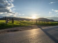 a lone country road is in the countryside area with mountains on both sides and barbed fence between the two sides