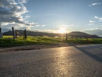 a lone country road is in the countryside area with mountains on both sides and barbed fence between the two sides