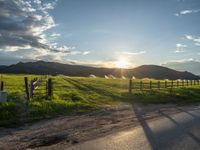 a lone country road is in the countryside area with mountains on both sides and barbed fence between the two sides