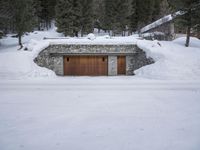 there is a covered garage under the snow with an open door on it near many trees
