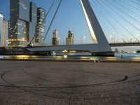 this bridge is in a wide city at twilight next to the water and tall buildings