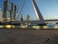 this bridge is in a wide city at twilight next to the water and tall buildings