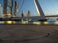 this bridge is in a wide city at twilight next to the water and tall buildings