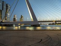 this bridge is in a wide city at twilight next to the water and tall buildings