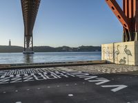 there are several letters painted on the side of a bridge and a boat sits in the water