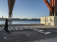 there are several letters painted on the side of a bridge and a boat sits in the water