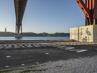 there are several letters painted on the side of a bridge and a boat sits in the water