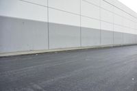 a white building on the street next to the road with a white line painted on the side