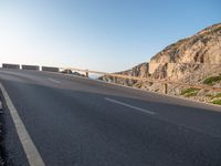 an empty road going past a cliff on a clear day in europe a few feet above ground