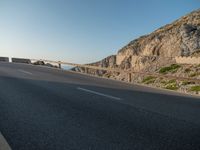 an empty road going past a cliff on a clear day in europe a few feet above ground