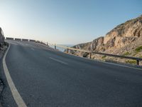 an empty road going past a cliff on a clear day in europe a few feet above ground