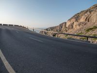 an empty road going past a cliff on a clear day in europe a few feet above ground