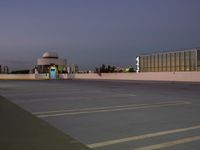 a picture of an empty parking lot with cars parked outside of it with building lights in the background